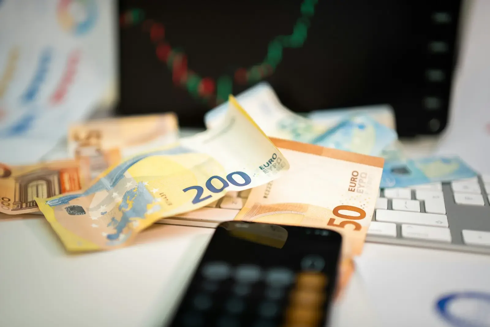 Imagen de diferentes billetes con una calculadora y un teclado de ordenador a su lado.