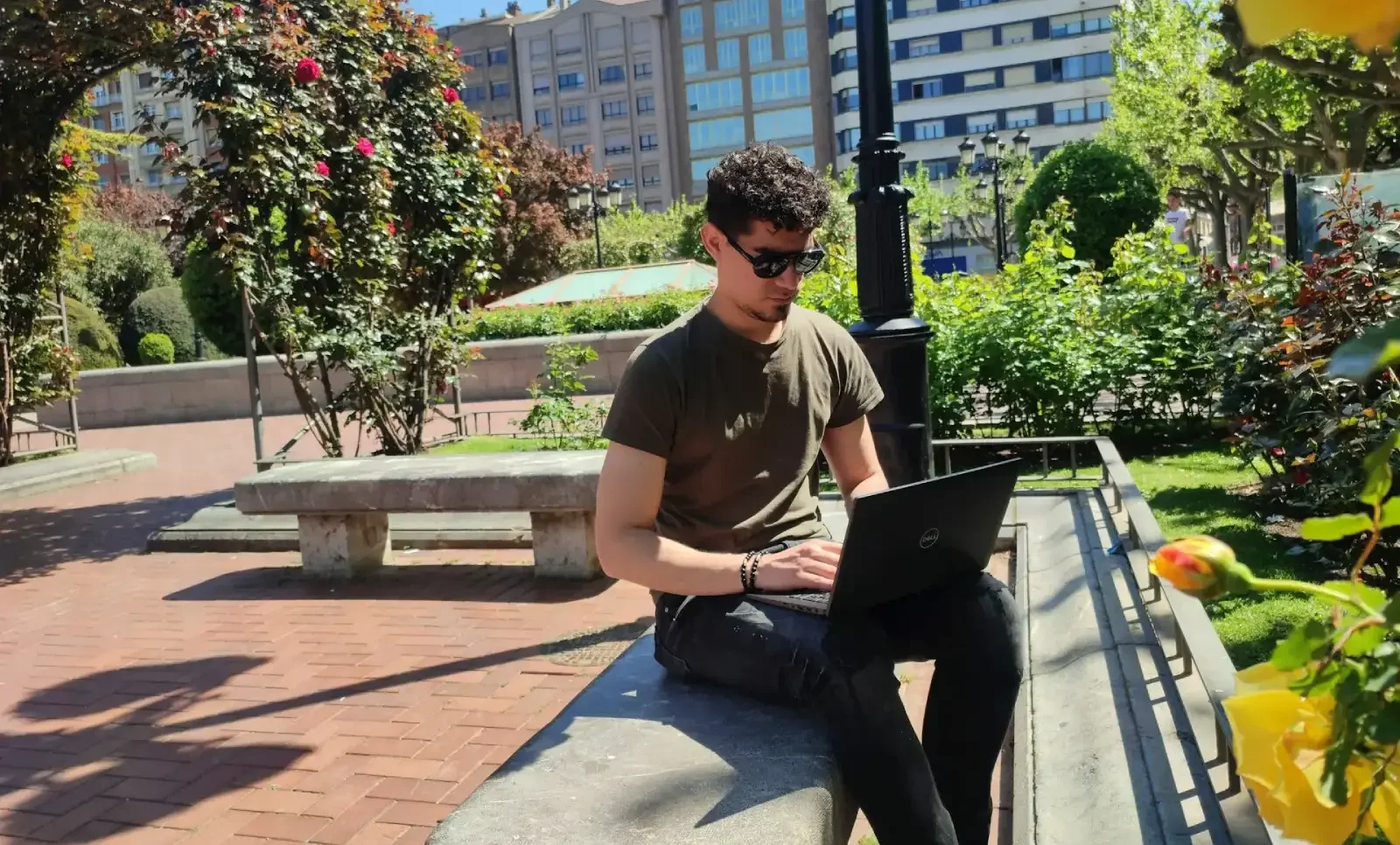 Hombre joven trabaja desde un parque con su ordenador portátil