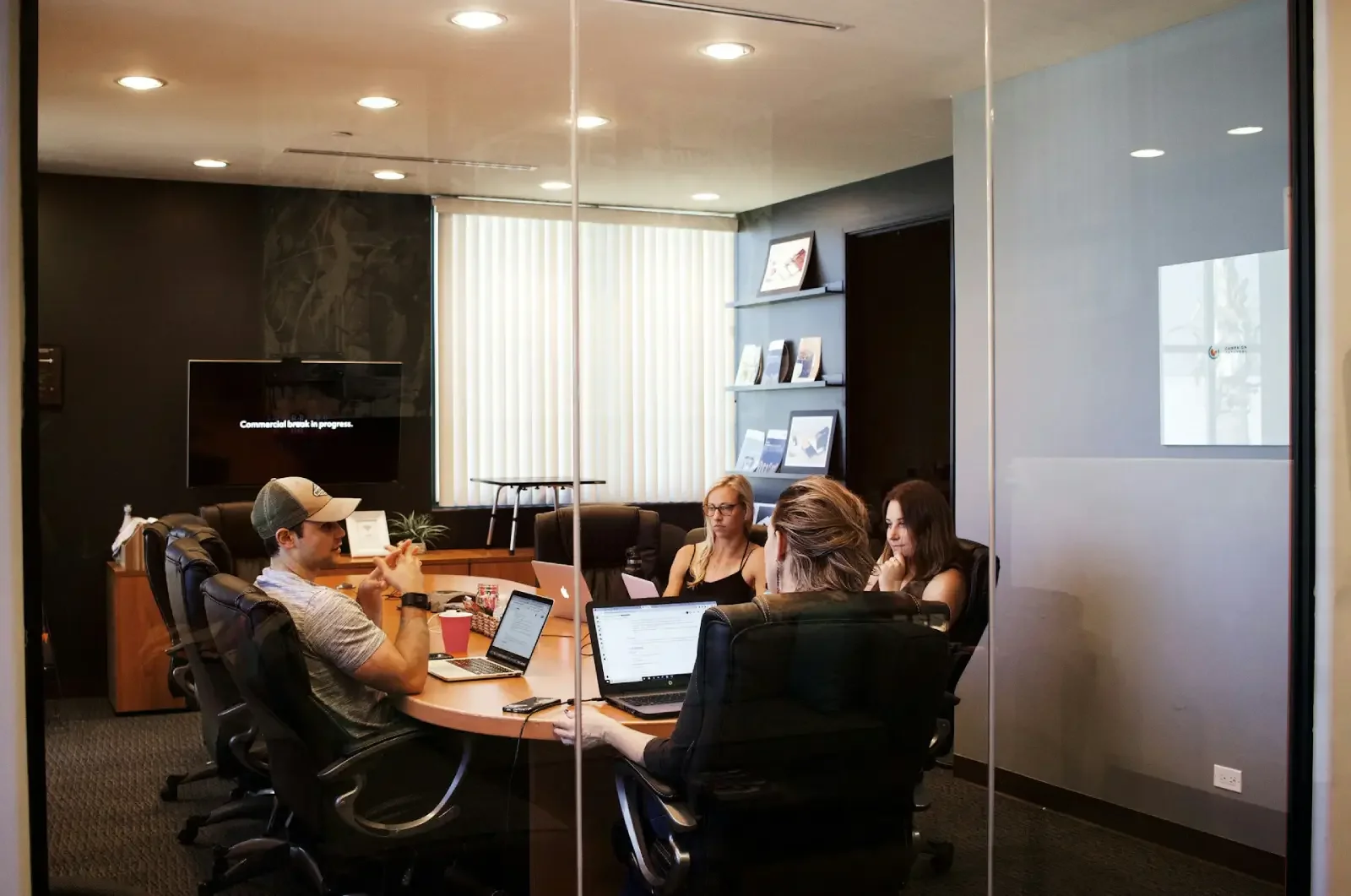Reunión de una empresa, con tres mujeres y un hombre con gorra