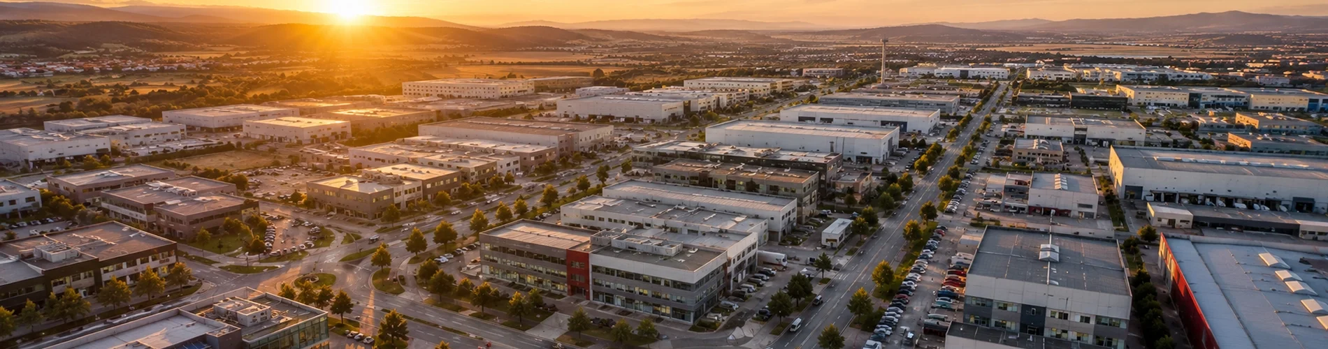 ) Vista aérea de un ecosistema empresarial con naves, oficinas y actividad económica al amanecer