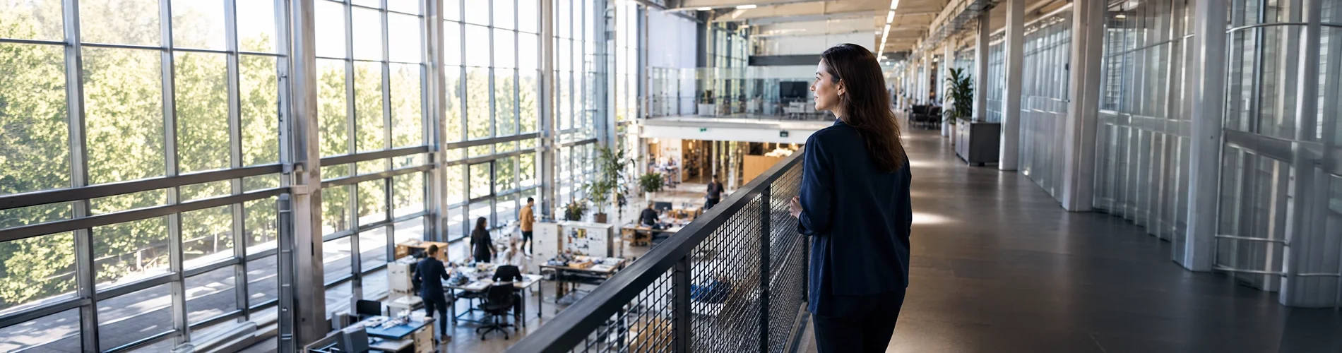 Empresaria observando la actividad de una empresa desde una pasarela que simboliza la conexión entre las empresas y la financiación